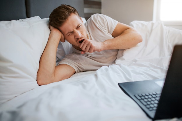 Young tired man lying in bed this morning