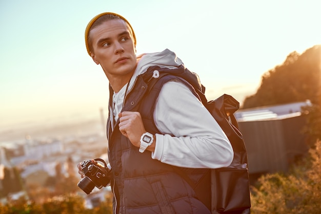 Young tourist blogger in hat makes a photo of sunrise