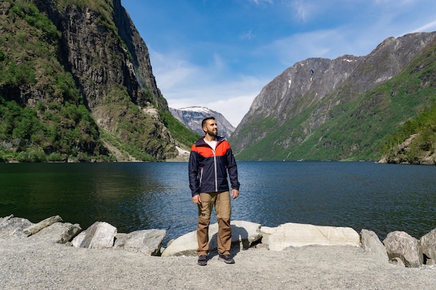 Young tourist boy at the foot of the fjord surrounded by high mountains in Gudvangen Norway