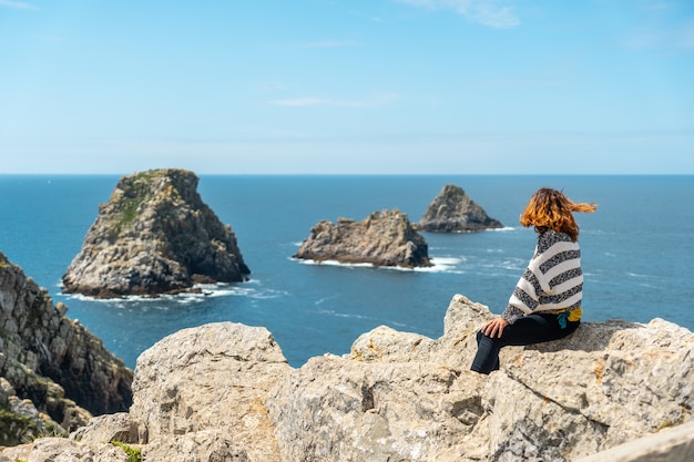 A young tourist girl looking at the sea at Pen Hir Point on the Crozon Peninsula in French Brittany, the three famous islets, France