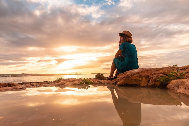 A young tourist sitting at sunset on the paseo de poniente in San Antonio Abad Ibiza Island Balearic