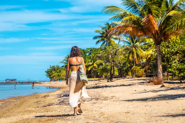 A young tourist walking along the beach of Sandy Bay on Roatan Island. Honduras