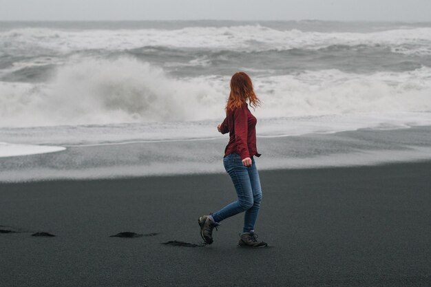 Photo young tourist walking along empty iceland beach scenic photography