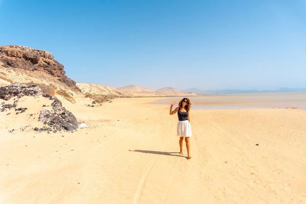 A young tourist walking along the Sotavento beach, ideal for sports such as Kitesurfing or sky surfing in the south of Fuerteventura, Canary Islands. Spain