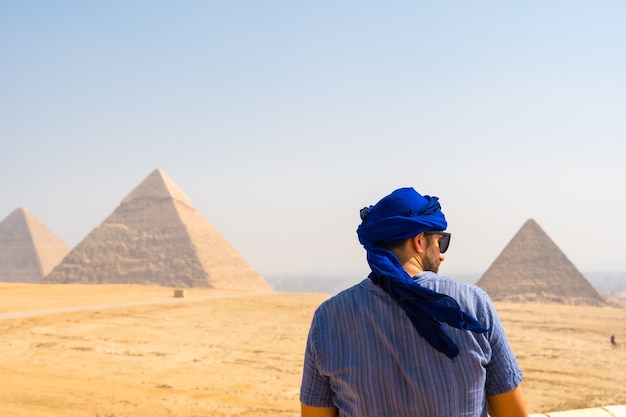 Young tourist wearing a blue turban and sunglasses enjoying the Pyramids of Giza, Cairo, Egypt