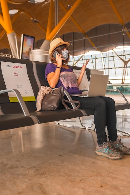 A young tourist with a face mask sitting waiting to take off airports almost empty