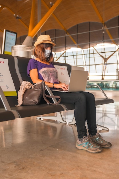 A young tourist with a face mask sitting waiting to take off airports almost empty