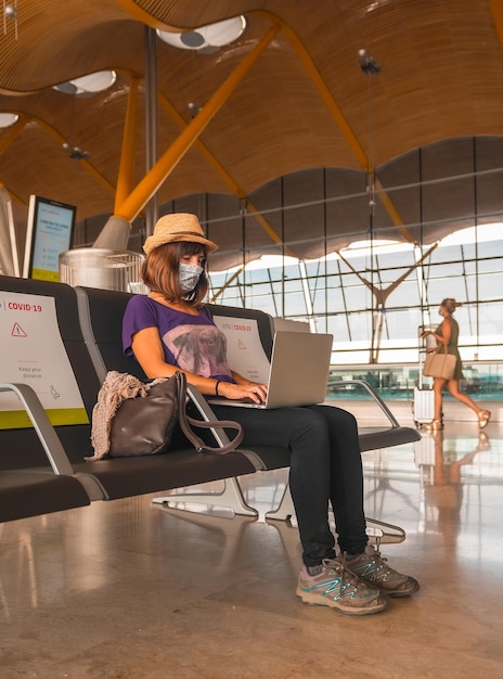 A young tourist with a face mask sitting waiting to take off airports almost empty