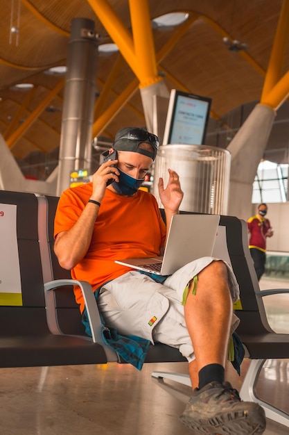 A young tourist with a face mask sitting waiting to take off airports almost empty