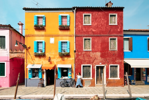 A young tourist woman in the colorful streets of Burano in Venice while smiling and visiting the italian city