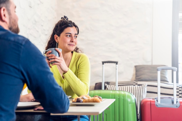 Young tourist woman having breakfast in a hotel restaurant with a man