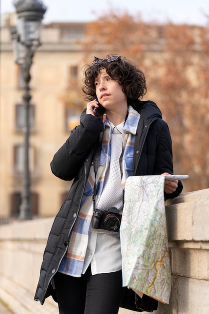 Young tourist woman with a map is talking on her phone in the street