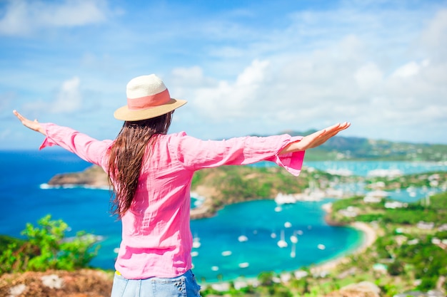 Young tourist woman with view of English Harbor from Shirley Heights, Antigua, paradise bay at tropical island in the Caribbean Sea