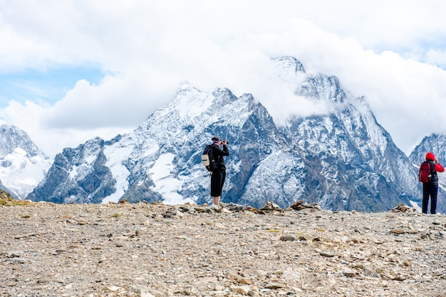 Young tourists in jackets take pictures of snowy rocks from the top of the mountain