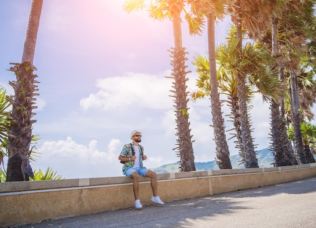 Young traveler man at summer holiday vacation with beautiful palms and seascapes at background