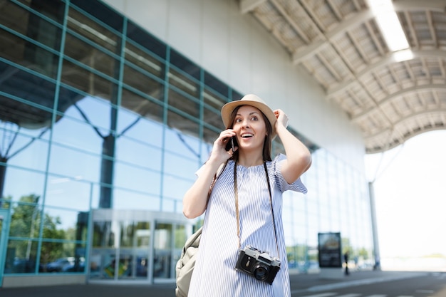 Young traveler tourist woman with retro vintage photo camera clingin to head talk on mobile phone call friend