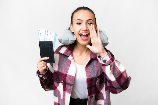 Young Traveler woman holding a passport over isolated white background shouting with mouth wide open