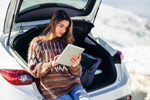 Young traveler woman using digital computer in snowy mountains in winter.