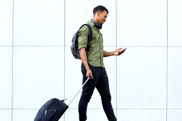 Photo young traveling man walking with suitcase and cellphone