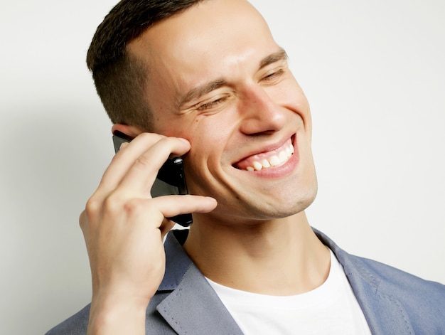 Young trendy man talking on cellphone, over white background