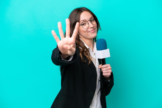 Young TV presenter woman isolated on blue background happy and counting four with fingers