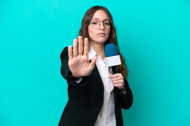 Young TV presenter woman isolated on blue background making stop gesture