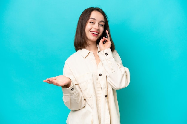 Young Ukrainian woman isolated on blue background keeping a conversation with the mobile phone with someone