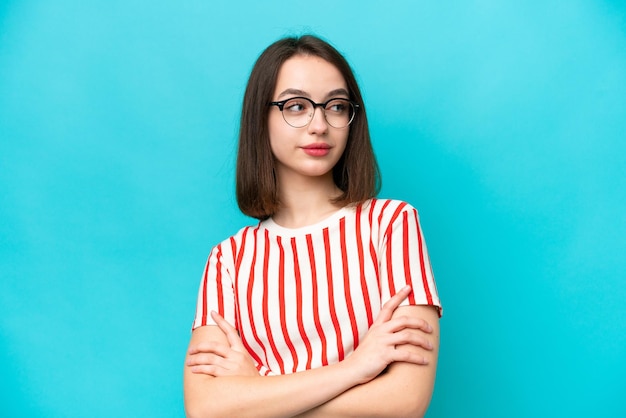 Young Ukrainian woman isolated on blue background looking to the side