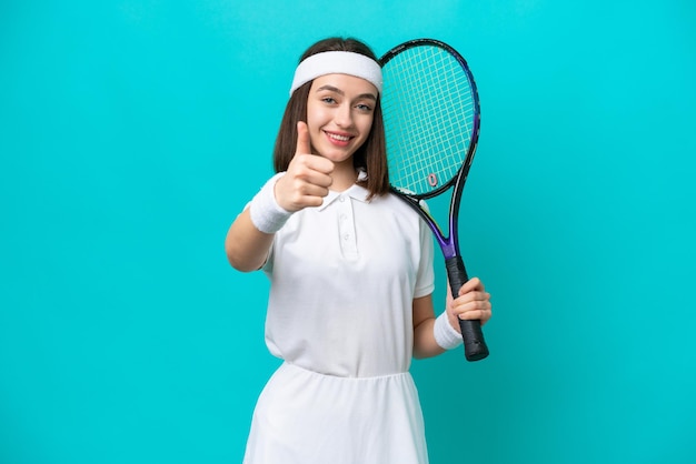 Young Ukrainian woman isolated on blue background playing tennis and with thumb up