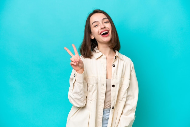 Young Ukrainian woman isolated on blue background smiling and showing victory sign