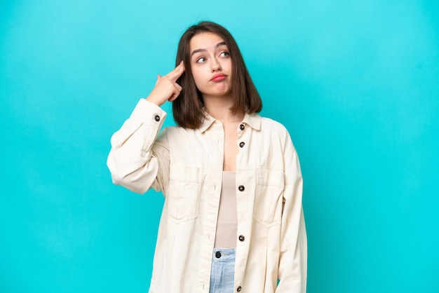 Young Ukrainian woman isolated on blue background with problems making suicide gesture