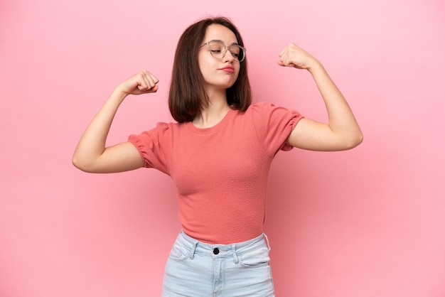 Young Ukrainian woman isolated on pink background doing strong gesture