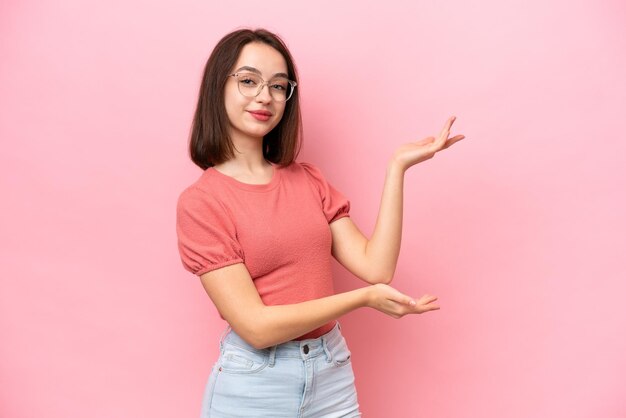 Young Ukrainian woman isolated on pink background extending hands to the side for inviting to come