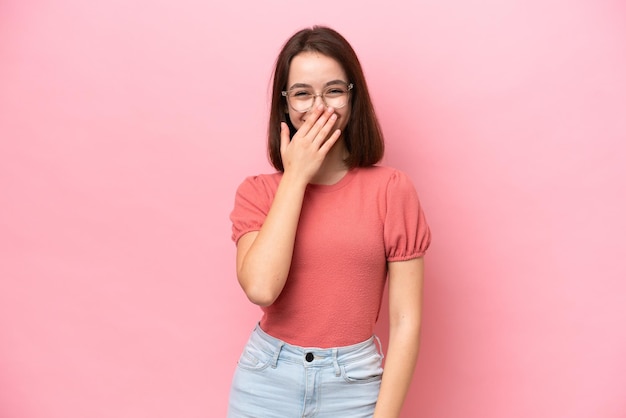 Young Ukrainian woman isolated on pink background happy and smiling covering mouth with hand