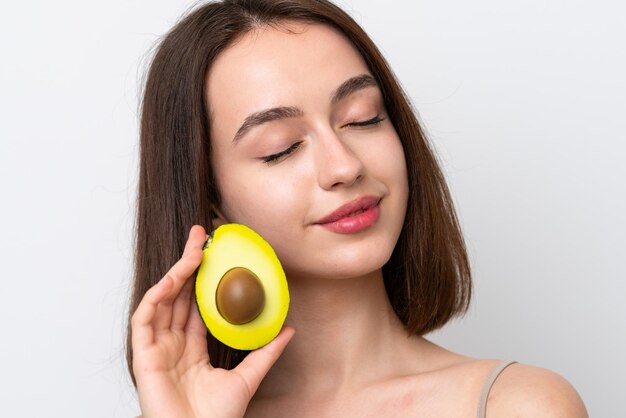 Young Ukrainian woman isolated on white background holding an avocado Close up portrait