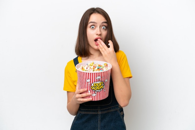 Young Ukrainian woman isolated on white background holding a big bucket of popcorns