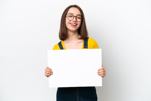 Young Ukrainian woman isolated on white background holding an empty placard with happy expression