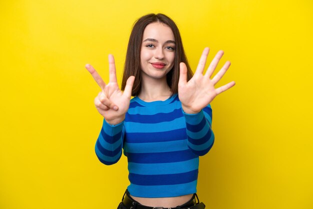 Young Ukrainian woman isolated on yellow background counting eight with fingers