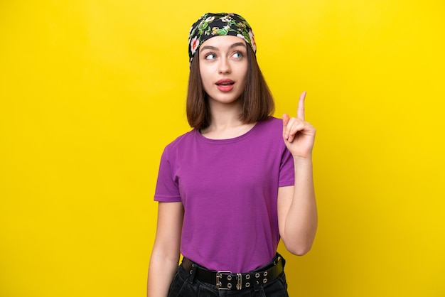 Young Ukrainian woman isolated on yellow background thinking an idea pointing the finger up