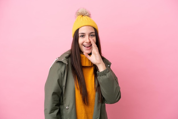 Young Ukrainian woman wearing winter jacket isolated on pink background shouting with mouth wide open