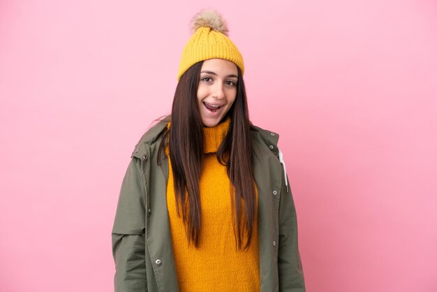 Young Ukrainian woman wearing winter jacket isolated on pink background with surprise facial expression