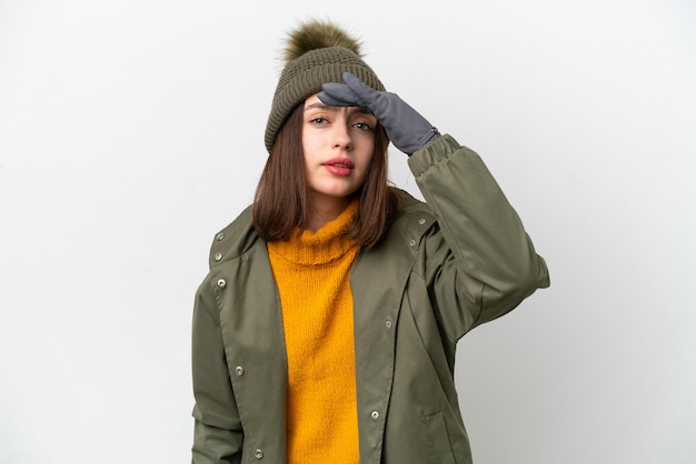 Young Ukrainian woman wearing winter jacket isolated on white background looking far away with hand to look something