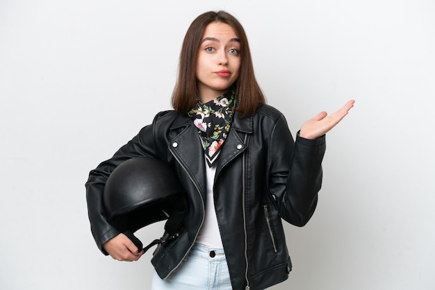 Young Ukrainian woman with a motorcycle helmet isolated on white background having doubts while raising hands