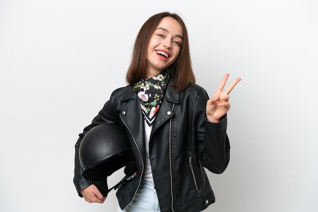 Young Ukrainian woman with a motorcycle helmet isolated on white background smiling and showing victory sign