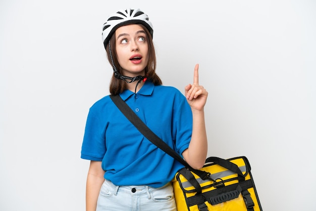 Young Ukrainian woman with thermal backpack isolated on white background pointing up and surprised