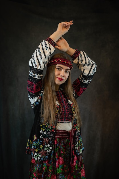 The young Ukrainian woman worn the traditional outfit of embroidery and poses in the studio