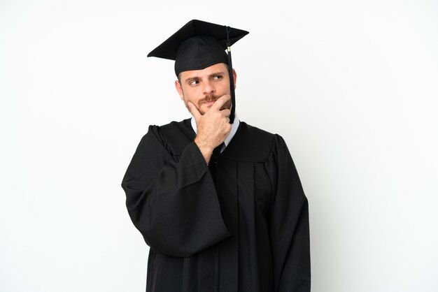 Young university Brazilian graduate isolated on white background having doubts