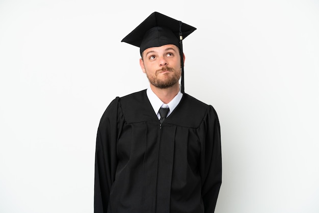 Young university Brazilian graduate isolated on white background and looking up