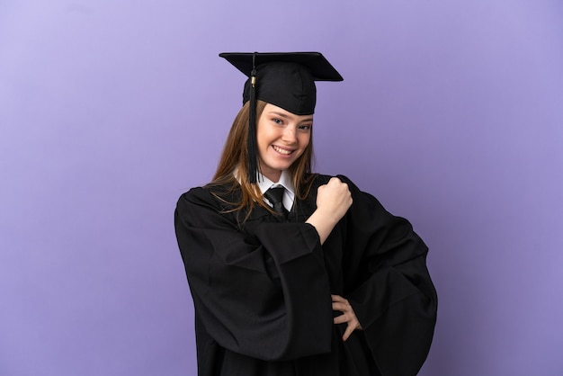 Young university graduate over isolated purple surface celebrating a victory