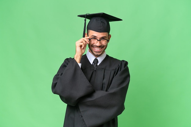 Young university graduate man over isolated background with glasses and happy